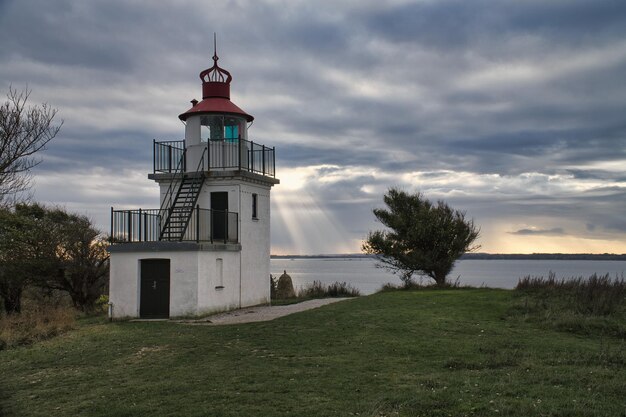 Lighthouse Spodsbjerg Fyr in Huntsted on the coast of Denmark Sun rays shining