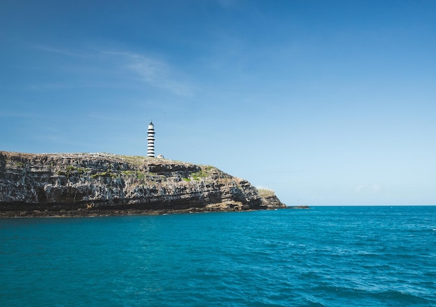 Lighthouse on top of cliffs in a blue sea in the Abrolhos Archipelago