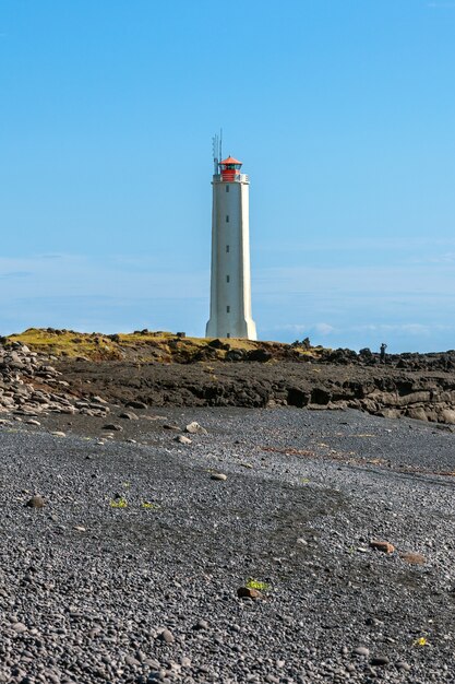 Foto faro sulla costa occidentale dell'islanda a tempo soleggiato. colpo verticale