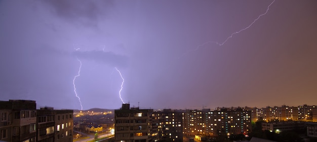 Un fulmine lampeggiante sopra la città estiva piovosa di notte