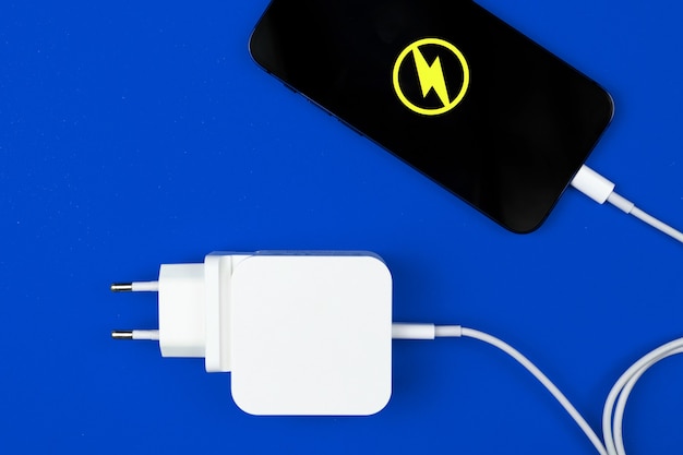 Photo lightning mobile charger. smartphone with energy icon and power charger on blue background. top view, flat lay photo