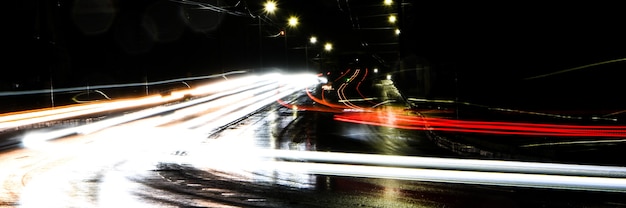 Lights of cars at night. Street lights. Night city. Long-exposure photograph night road. Colored bands of light on the road. Wet road after rain.