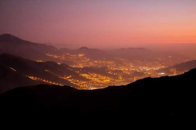 Lights of a city in the distance seen from the top of a mountain