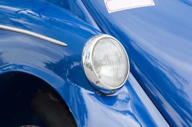 Lights in front of a vintage car with a unique sphere.