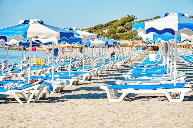 Ligstoelen en parasols in blauwe en witte kleur op het strand