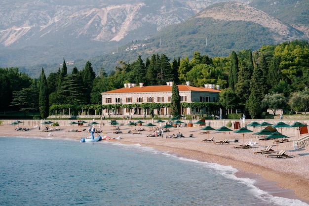 Ligstoelen en parasols op het strand bij villa milocer montenegro