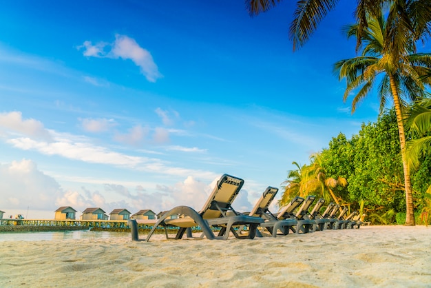 Ligstoelen in het eiland van de Maldiven met watervilla&#39;s in de zonsopgangtijd.