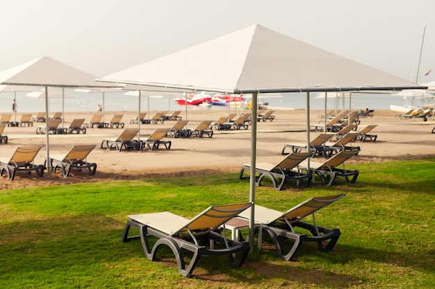 Ligstoelen met parasols op het strand, perspectief. hotel, zomervakantie