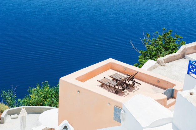 Ligstoelen op het terras met uitzicht op zee. Witte architectuur op het eiland Santorini, Griekenland.