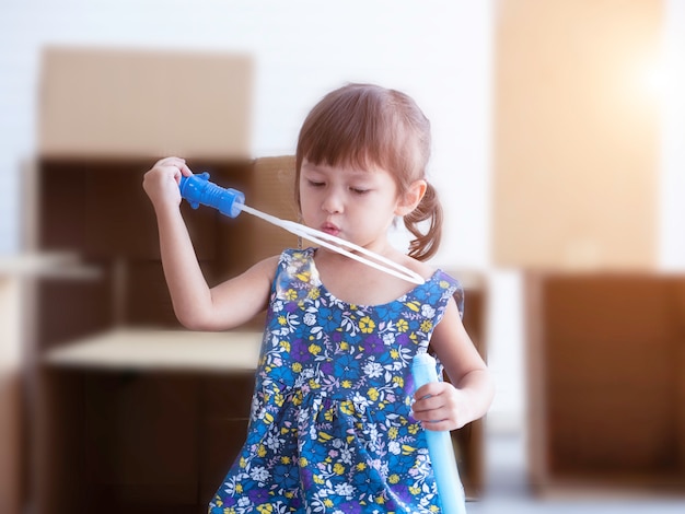 Liitle cute girl blowing soap bubbles in playroom.