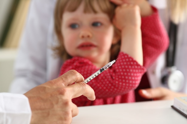 Liitle kid scared looking at the doctor before vaccination