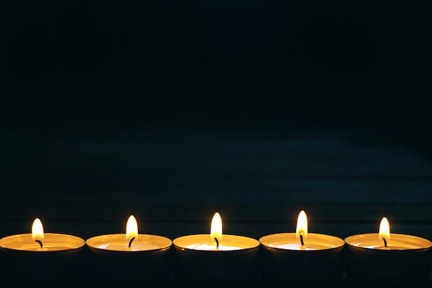 Lijn van vijf brandende kaarsen op donker