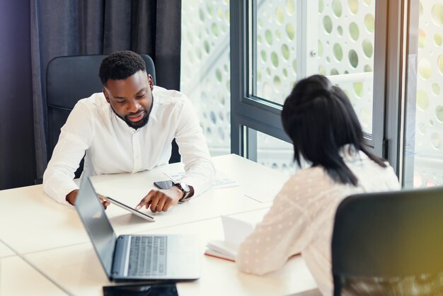 Likable purposeful business partners carefully studying financial documents with charts at the boardroom table at the meeting room.