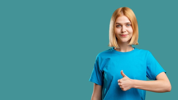 제스처 승인 기호 청록색 복사 공간 광고 배경 특별 제안에 격리된 엄지손가락으로 아이디어를 수락하는 파란색 티셔츠를 입은 만족한 행복한 열정적인 여성의 초상화
