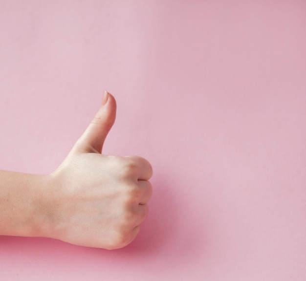 Like hand sign on a light trending pink background Successful concept female hand thumb up