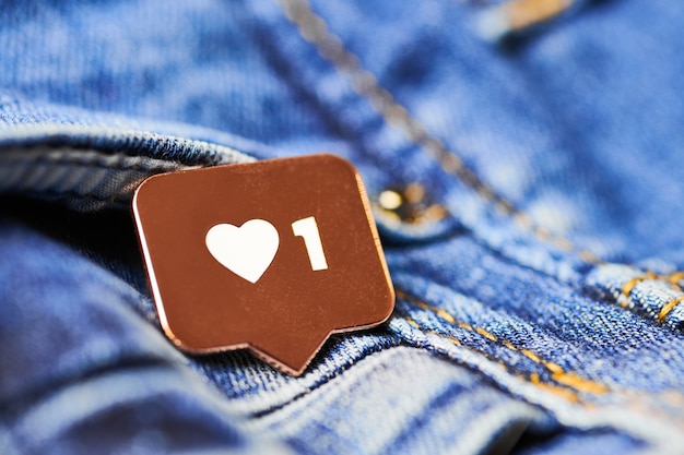 Like heart symbol. Like sign button, symbol with heart and one digit. Social media network marketing. Blue jeans texture background.
