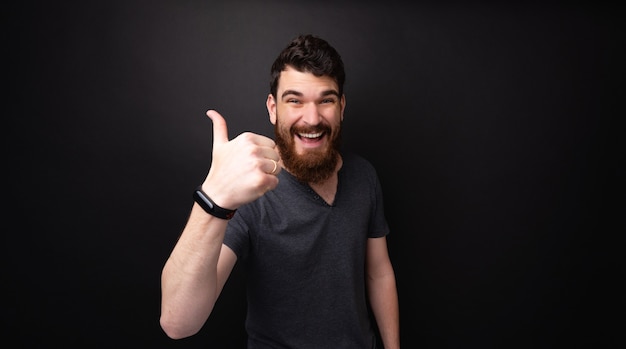 LIKE IT!!Photo of a barded guy showing thumb up, a like sign over dark background