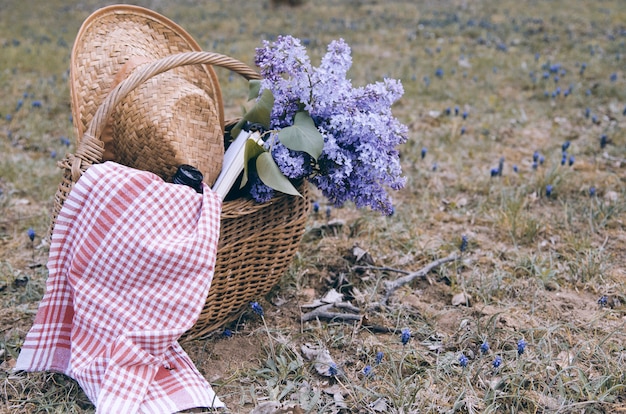 Lila bloemboeket in rieten mand met picknickbehoefte