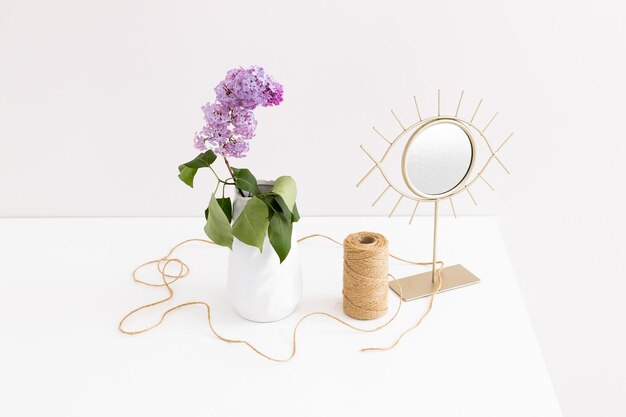 Lila bloemen in een vaas met touw en spiegel op een witte tafel met lege kopieerruimte