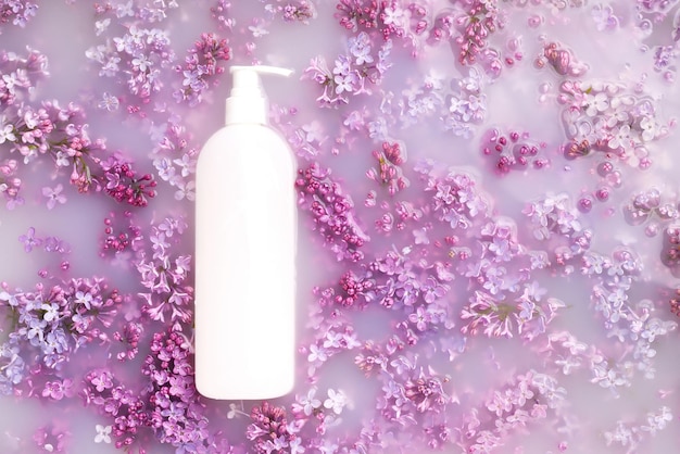 Lila bloemen in melk met een fles voor cosmetica foto van bovenaf met bloemen