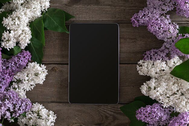 Lilac blossom on rustic wooden background tablet with empty space for greeting message top view