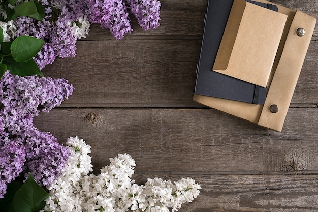 Lilac blossom on rustic wooden background with notebook for greeting message. Top view. Mother's Day. Spring background concept.