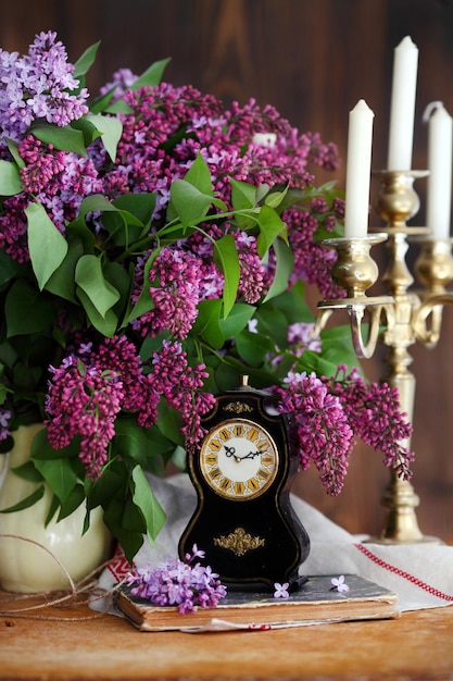 Lilac bouquet in ceramic jug lilac brush and forging candle holder with candles Still life