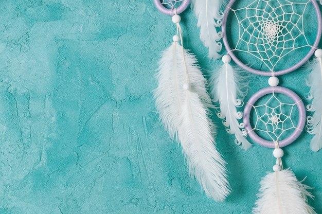 Photo lilac cream white dream catcher on aquamarine background. copy space for text.