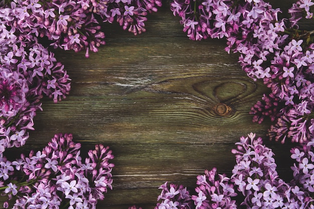 Lilac flowers on an old wooden background. A border of lilac flowers copy space.