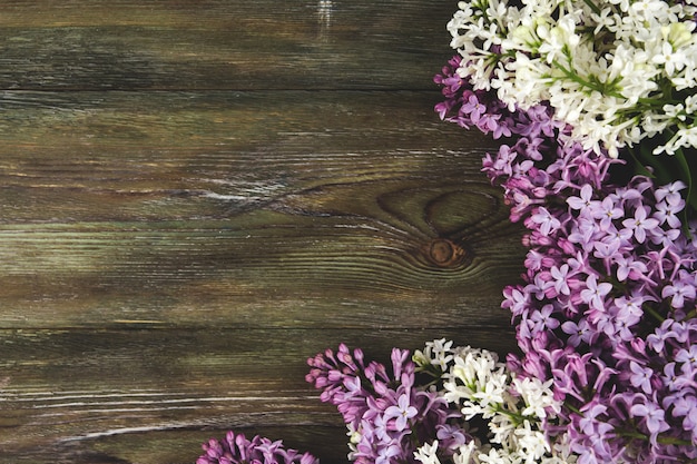 Lilac flowers on an old wooden background. A border of lilac flowers copy space.