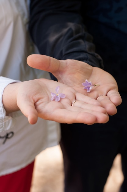 Lilac flowers in the palms of a girl in red pants and a white jacket and a guy in dark clothes on a blurry background