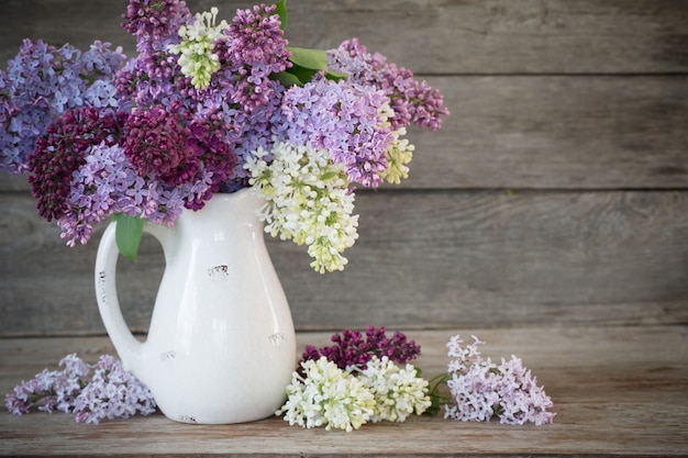 Lilac in jug on old wooden background