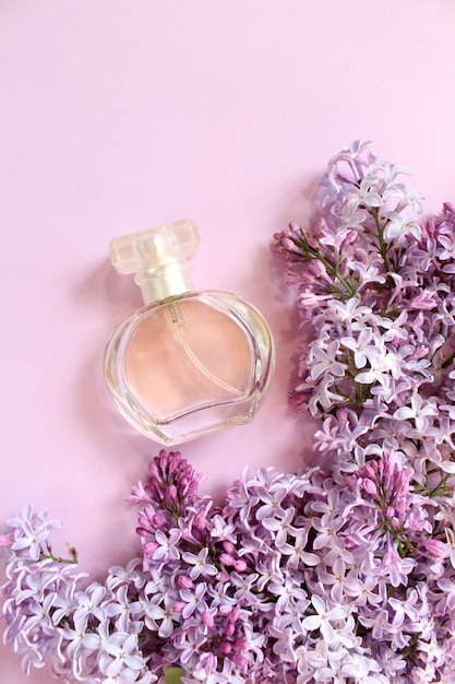 Lilac perfume bottle with spray of lilac flowers on background creative floral composition Close up Natural perfumery and floral scent concept Fresh spring fragrant