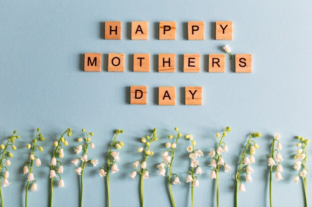 Lilies of the valley on the blue photo and the text in wooden letters "happy mother's day".