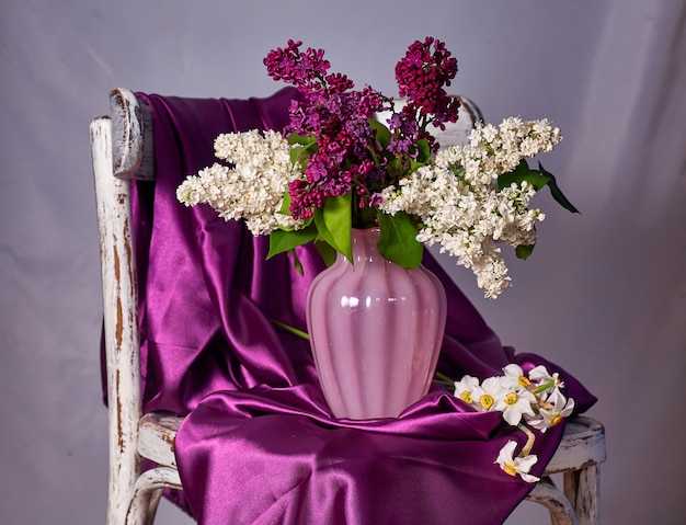 Photo lillac bouquet in vase on vintage wooden chair