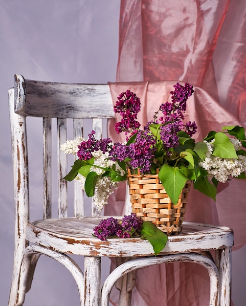 Photo lillac bouquet in vase on vintage wooden chair