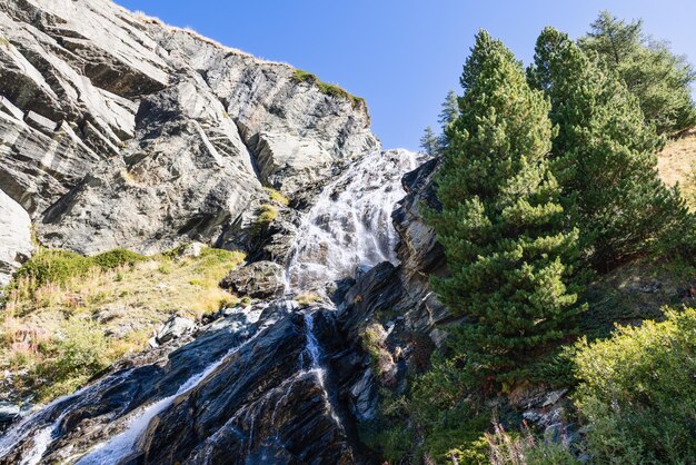 Foto lillaz cascata granito karst rapide alberi sempreverdi cielo blu valle d'aosta italia