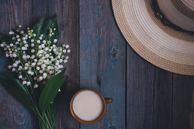 ユリの谷の花束、一杯のコーヒー、紅茶、牛乳、木製の背景に