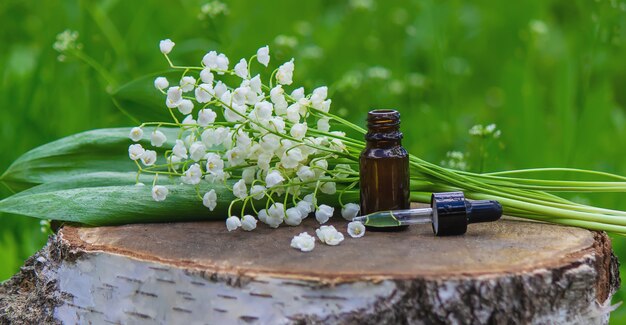 Lily of the valley essential oil in a small bottle. Selective focus. Nature.