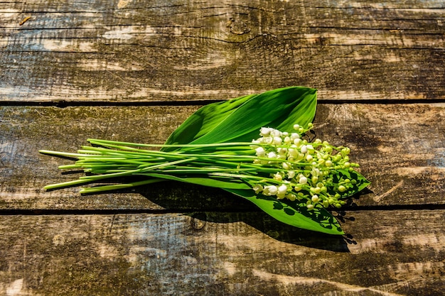 Lily of the valley flowers on rustic wooden background. Top view
