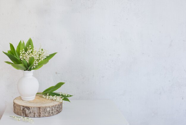 Lily of the valley in vase on old white wall