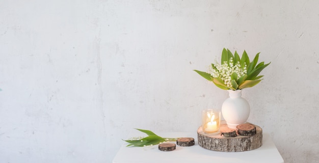 Lily of the valley in vase with candles