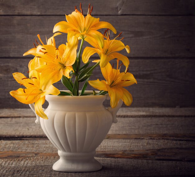 Lily in vase on wooden background