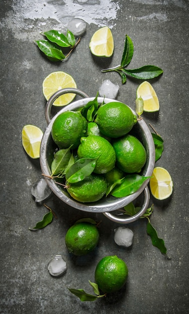 Lime background. Fresh limes in a saucepan with slices and leaves around.