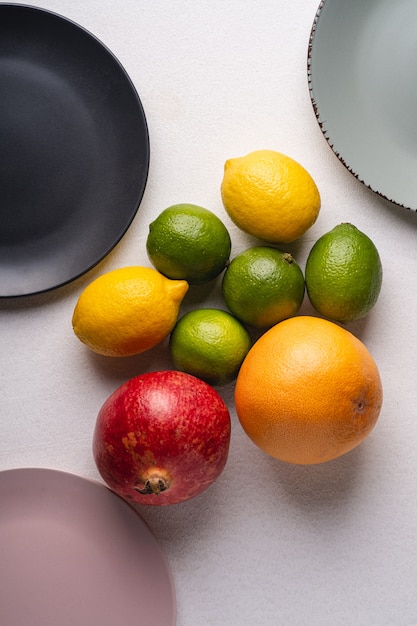 Лайм, лимон, грейпфрут и гранат с пустыми тарелками на белом