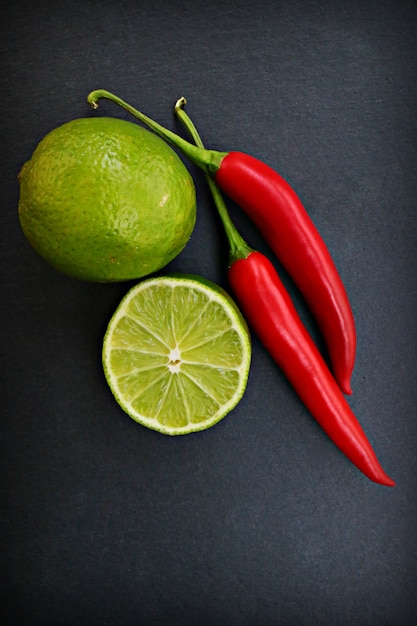 lime and red hot pepper on a black surface