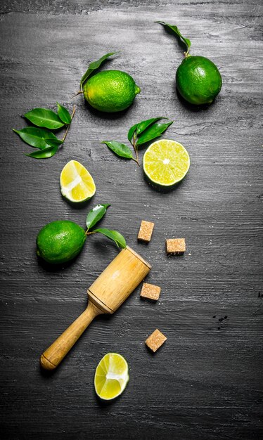 Foto tavolo di lime limette fresche con foglie, zucchero e pestello.