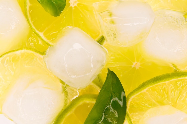 Lime with pieces of ice and green leaves Background