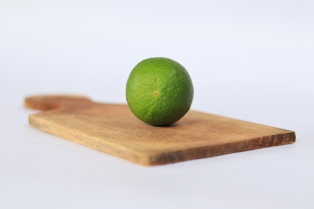 A lime on a wooden cutting board is on a white background.