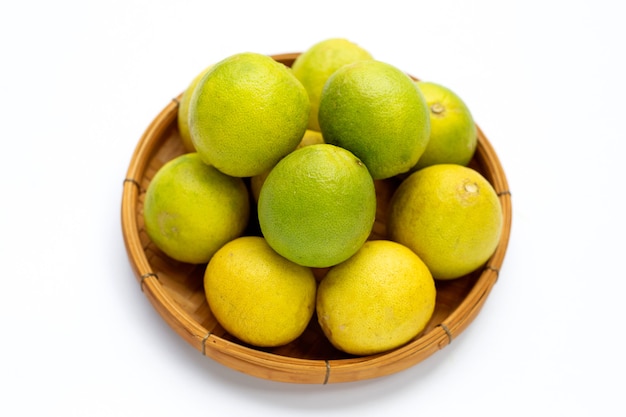 Limes in bamboo basket on white background.